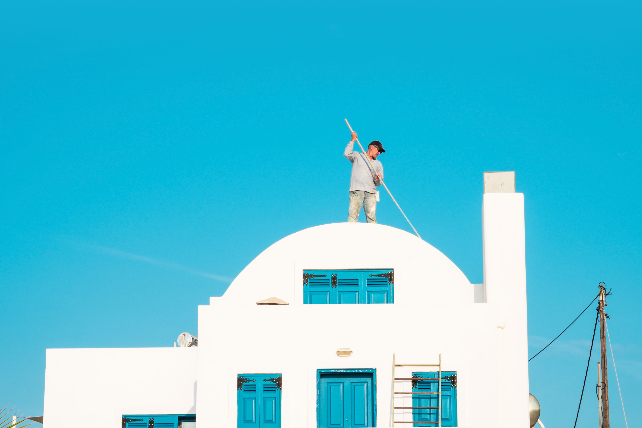 A man painting the roof in Santorini, Greece. Photo by Jari Anttonen.